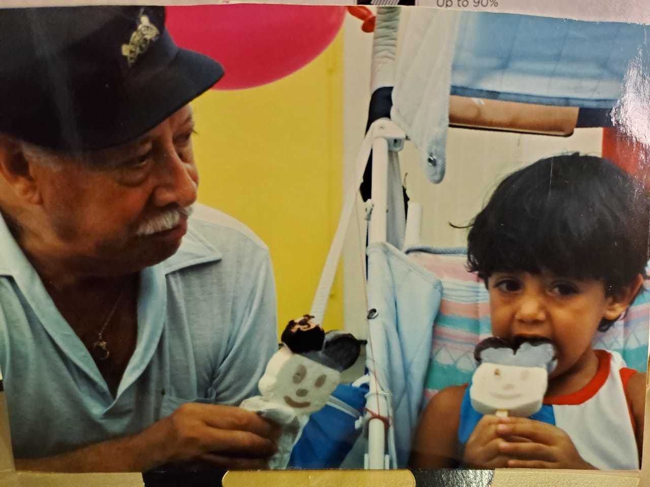 Carlos as a child eating icecream with an older gentleman.